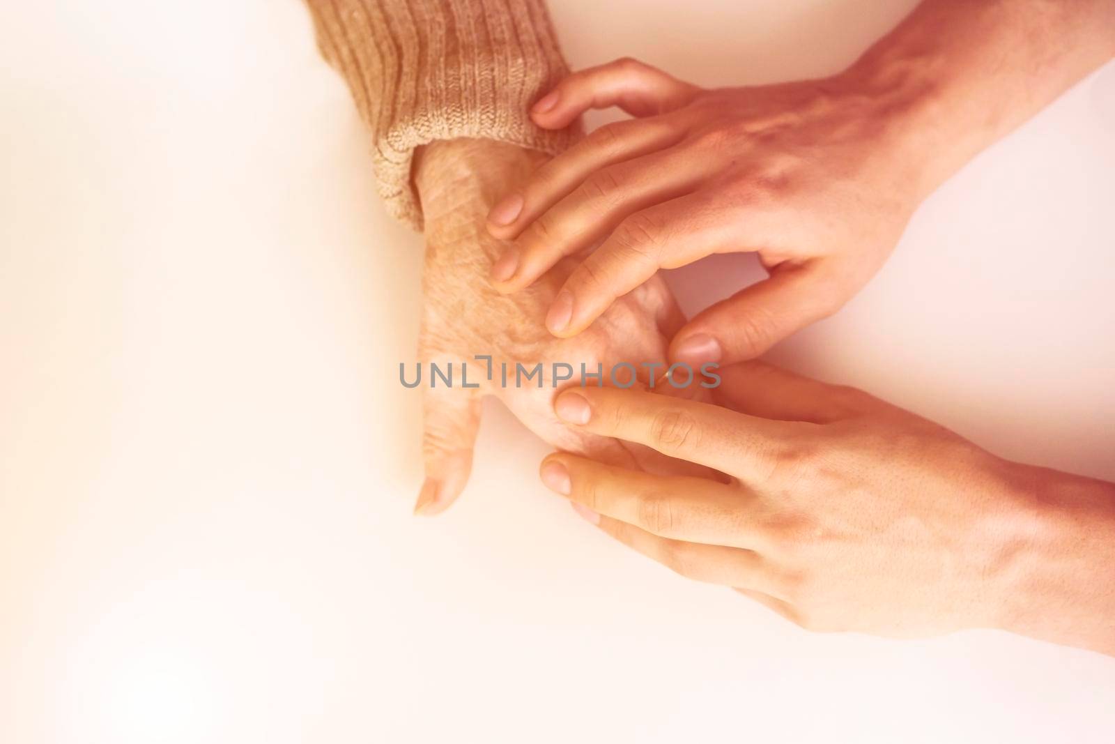 Young woman's hands hold grandmother's hands, an elderly patient. Handshake, caring, trust and support. Medicine, family and healthcare.