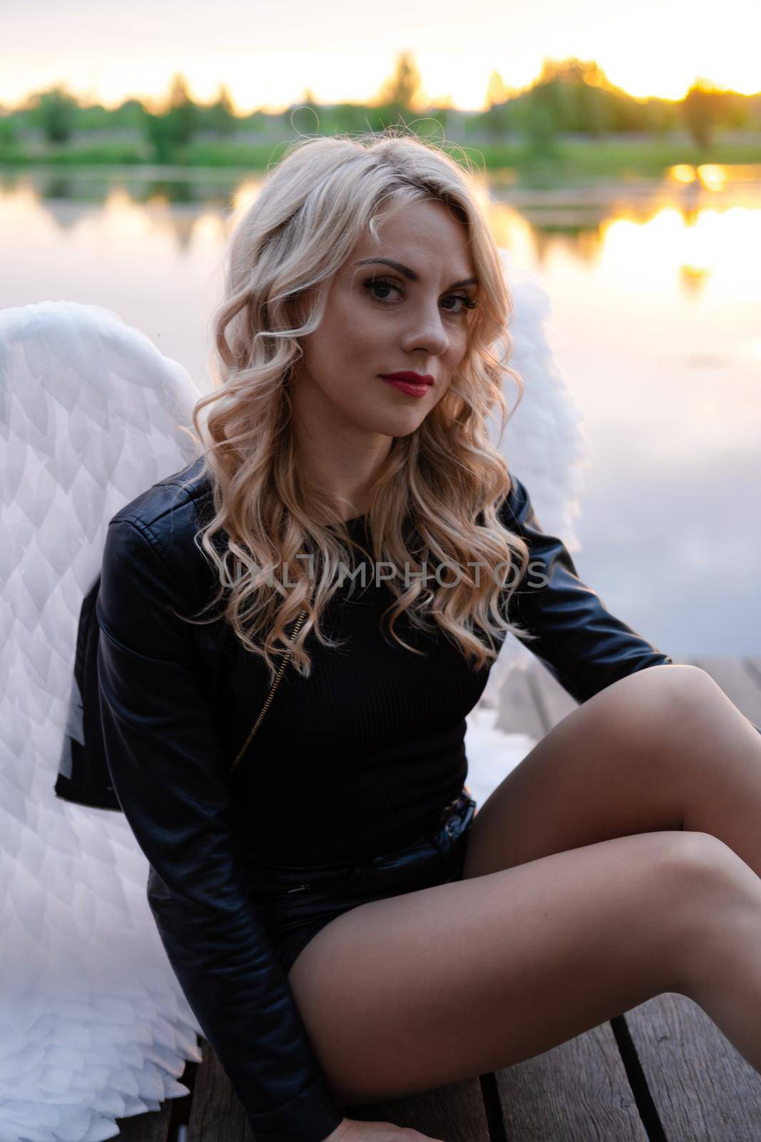 dark angel. blonde sexy woman in black leather clothes with white angels wings.