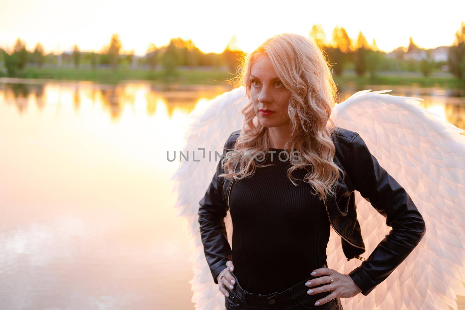 dark angel. blonde sexy woman in black leather clothes with white angels wings.