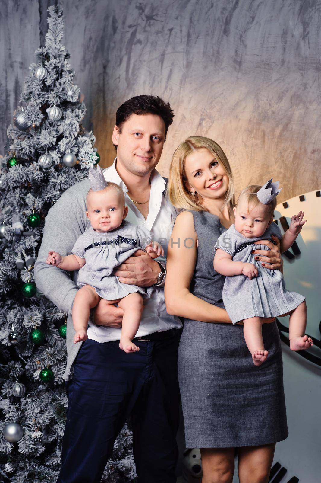 A happy big family with twin children in the New Year's interior of the house on the background of a Christmas tree.