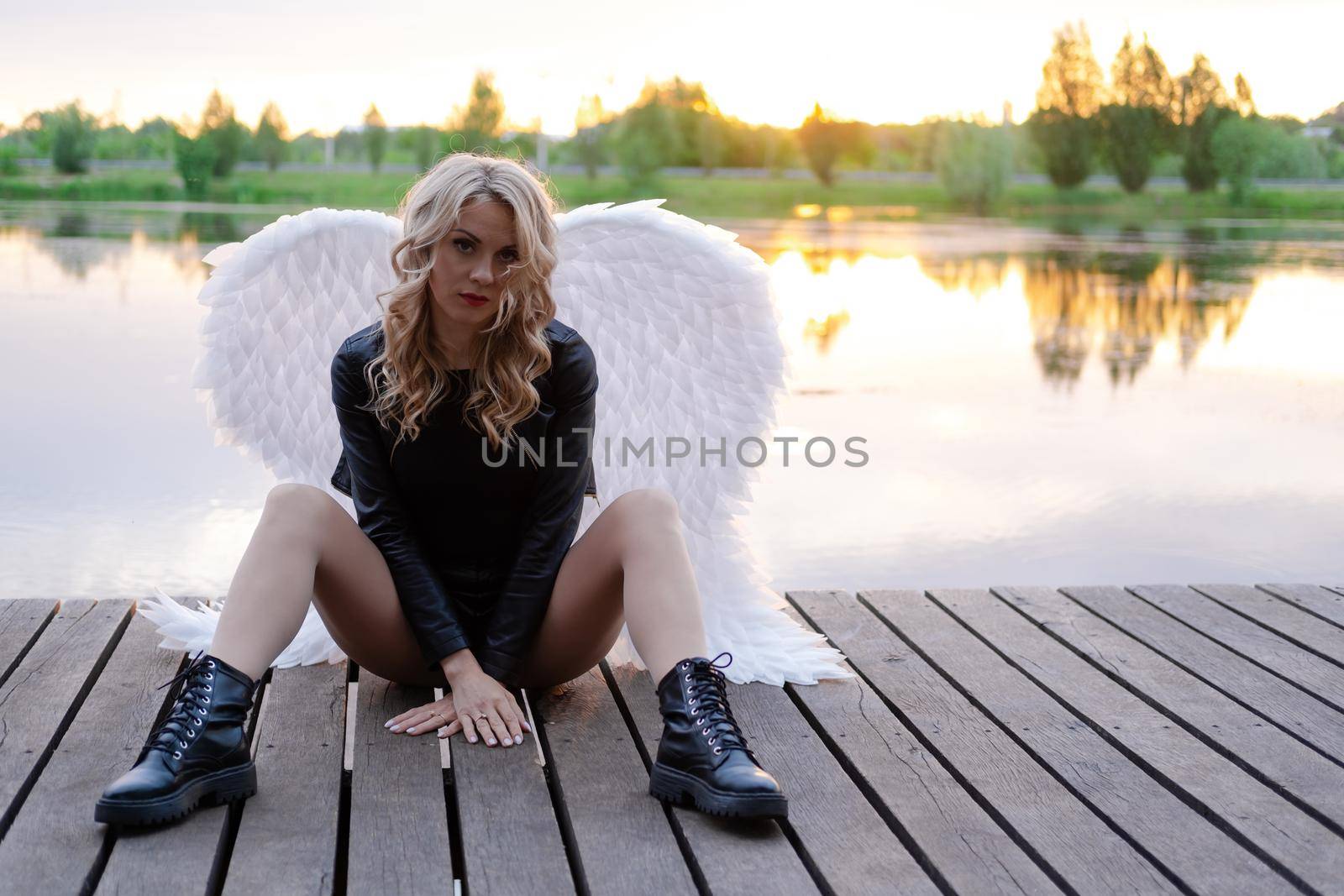 dark angel. blonde sexy woman in black leather clothes with white angels wings.