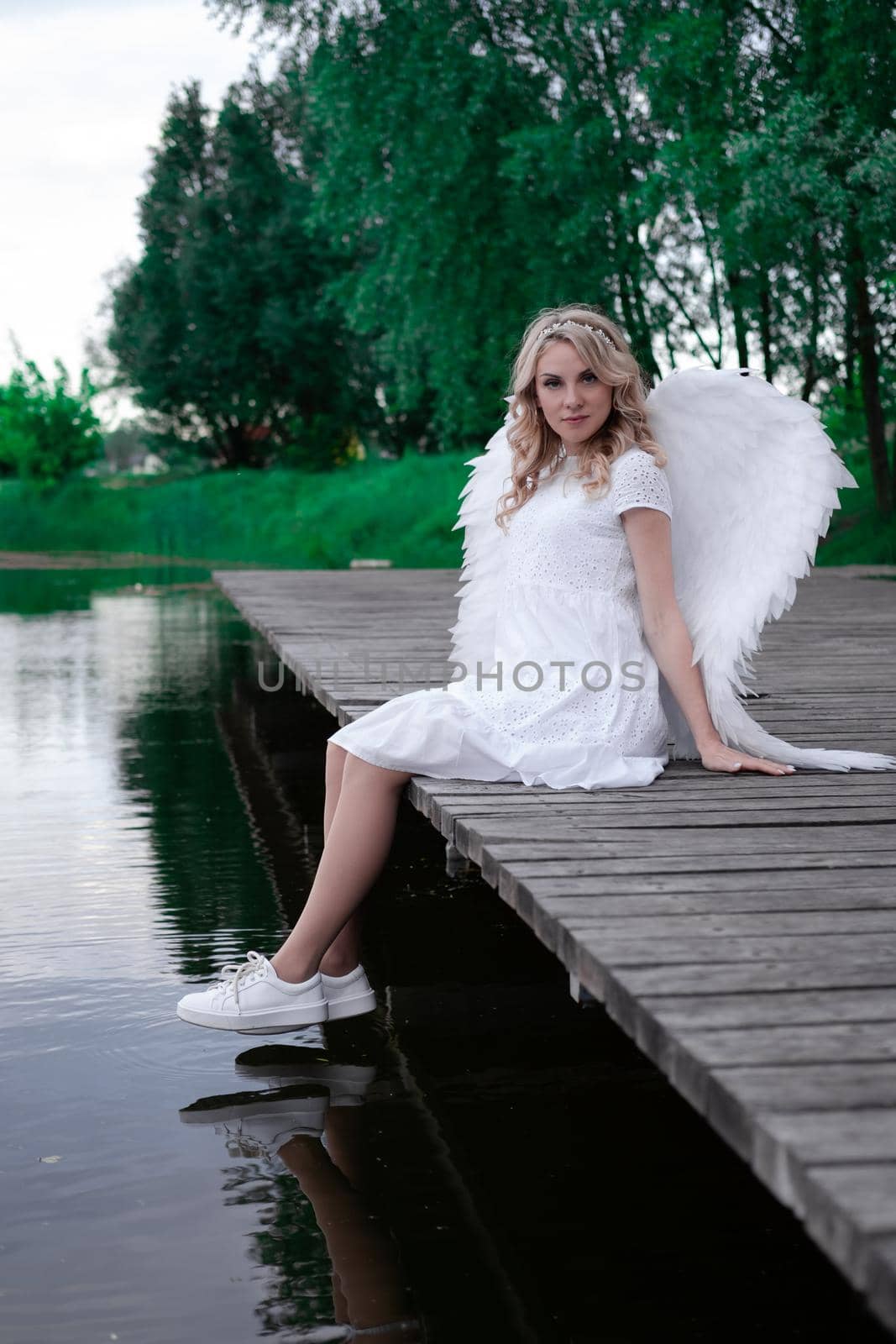 beautiful angel in white dress. Amazing blond woman with long curly hair and white wings