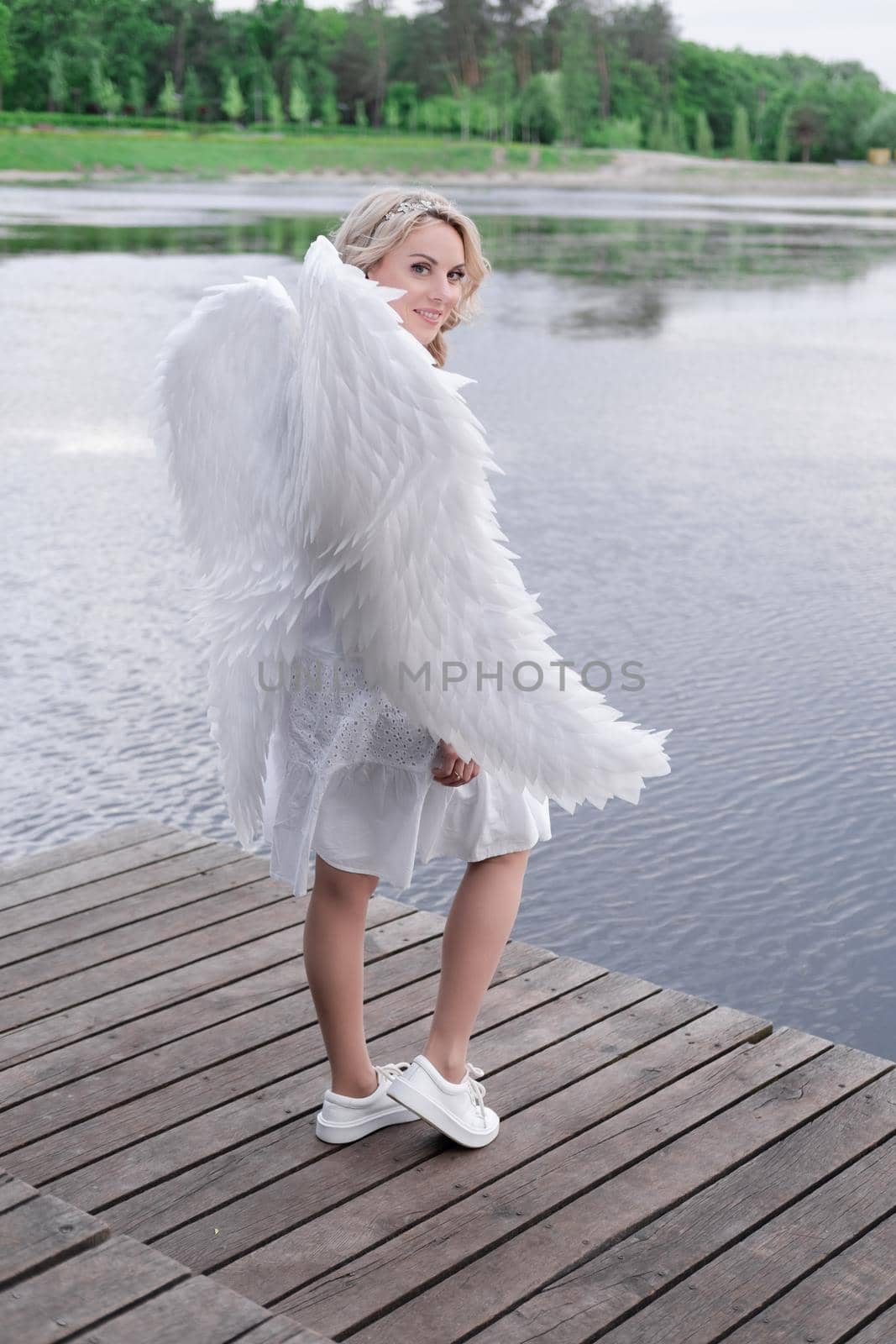 beautiful angel in white dress. Amazing blond woman with long curly hair and white wings