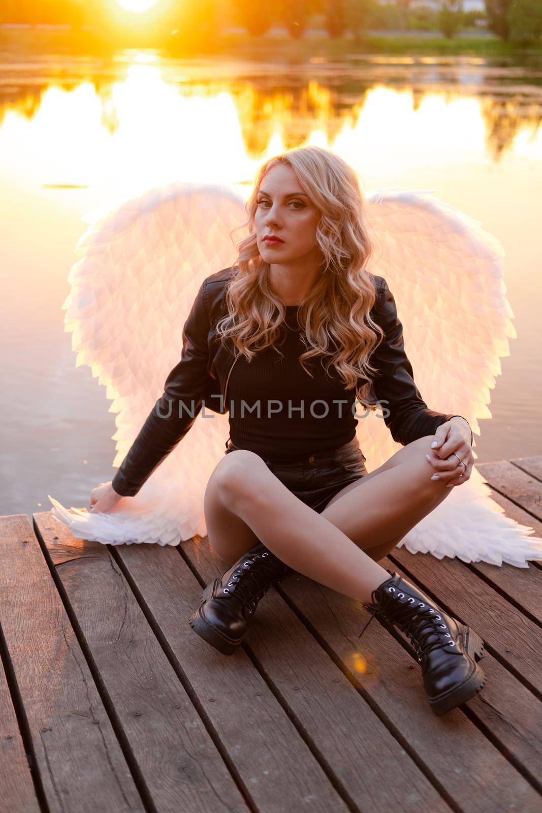 woman with white angel wings. wearing black leather clothes. fallen dark angel. demon. beast. girl in angel costume on halloween by oliavesna