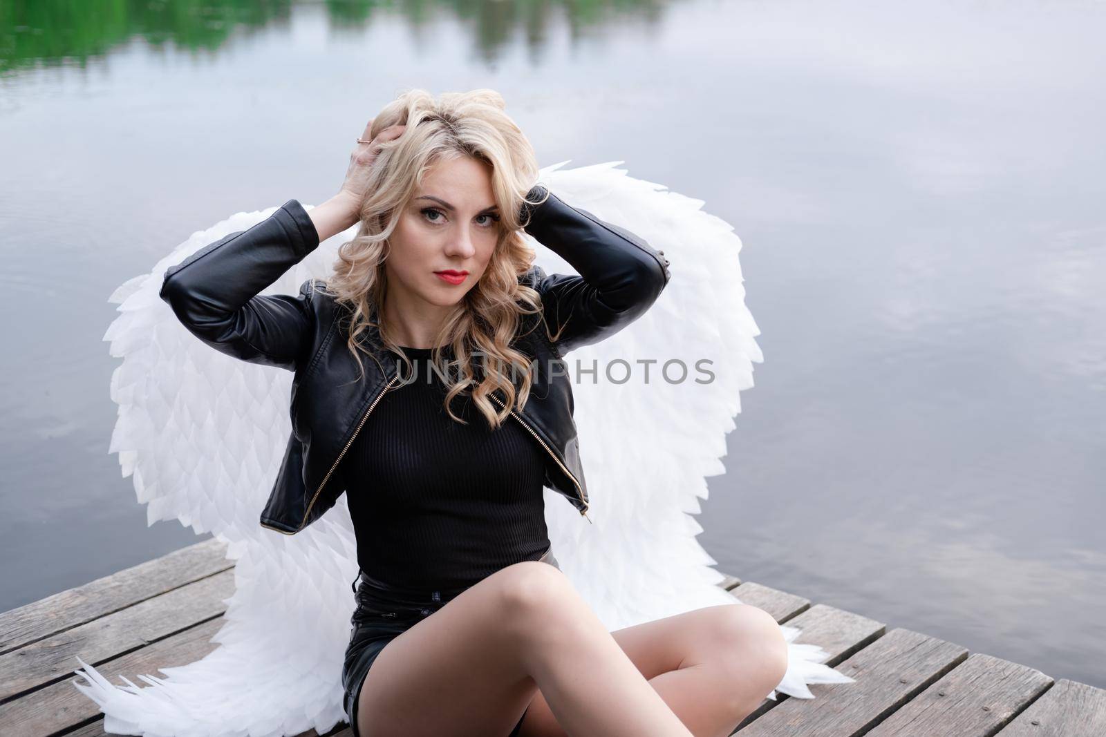 dark angel. blonde sexy woman in black leather clothes with white angels wings.