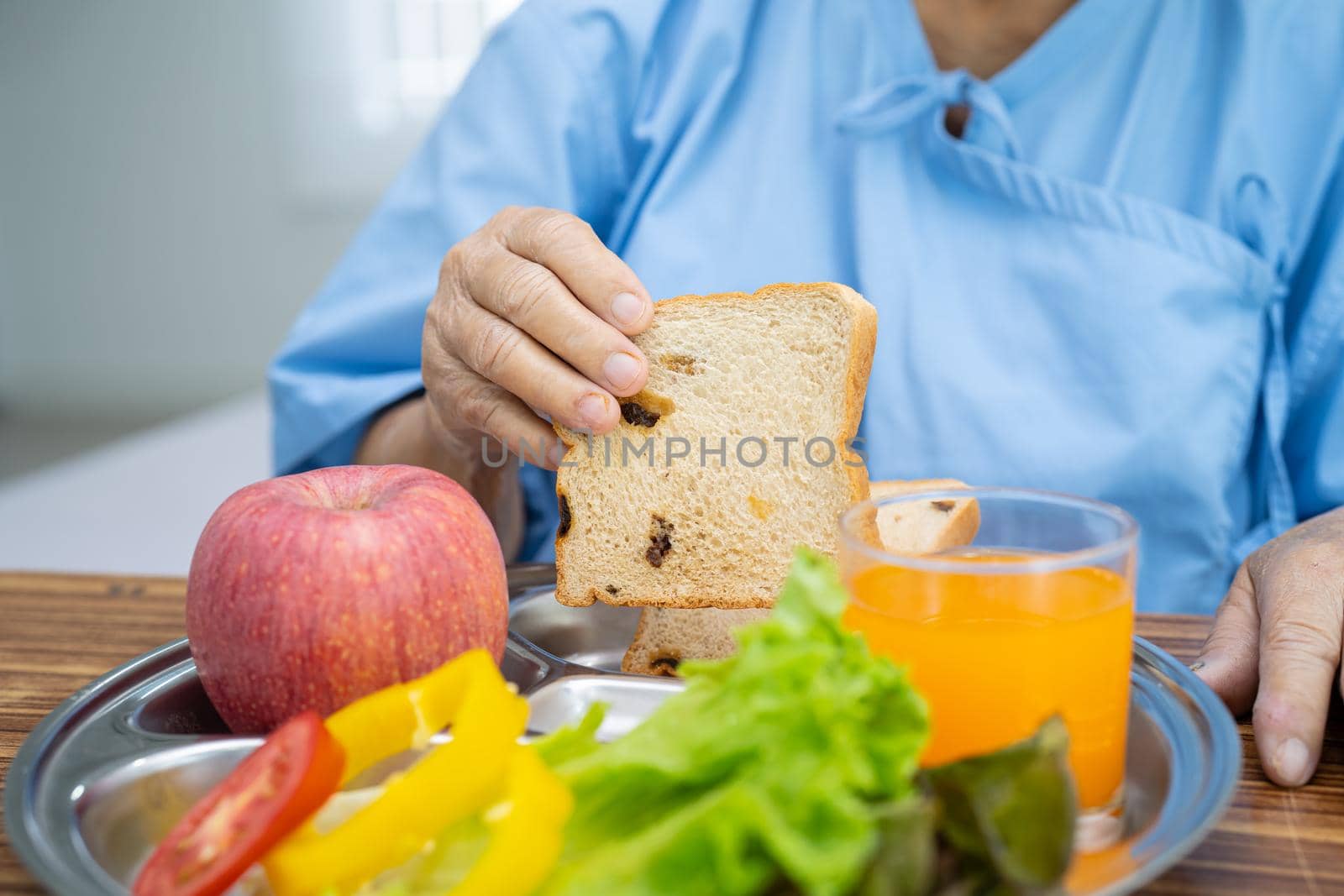 Asian senior or elderly old lady woman patient eating breakfast vegetable healthy food with hope and happy while sitting and hungry on bed in hospital.