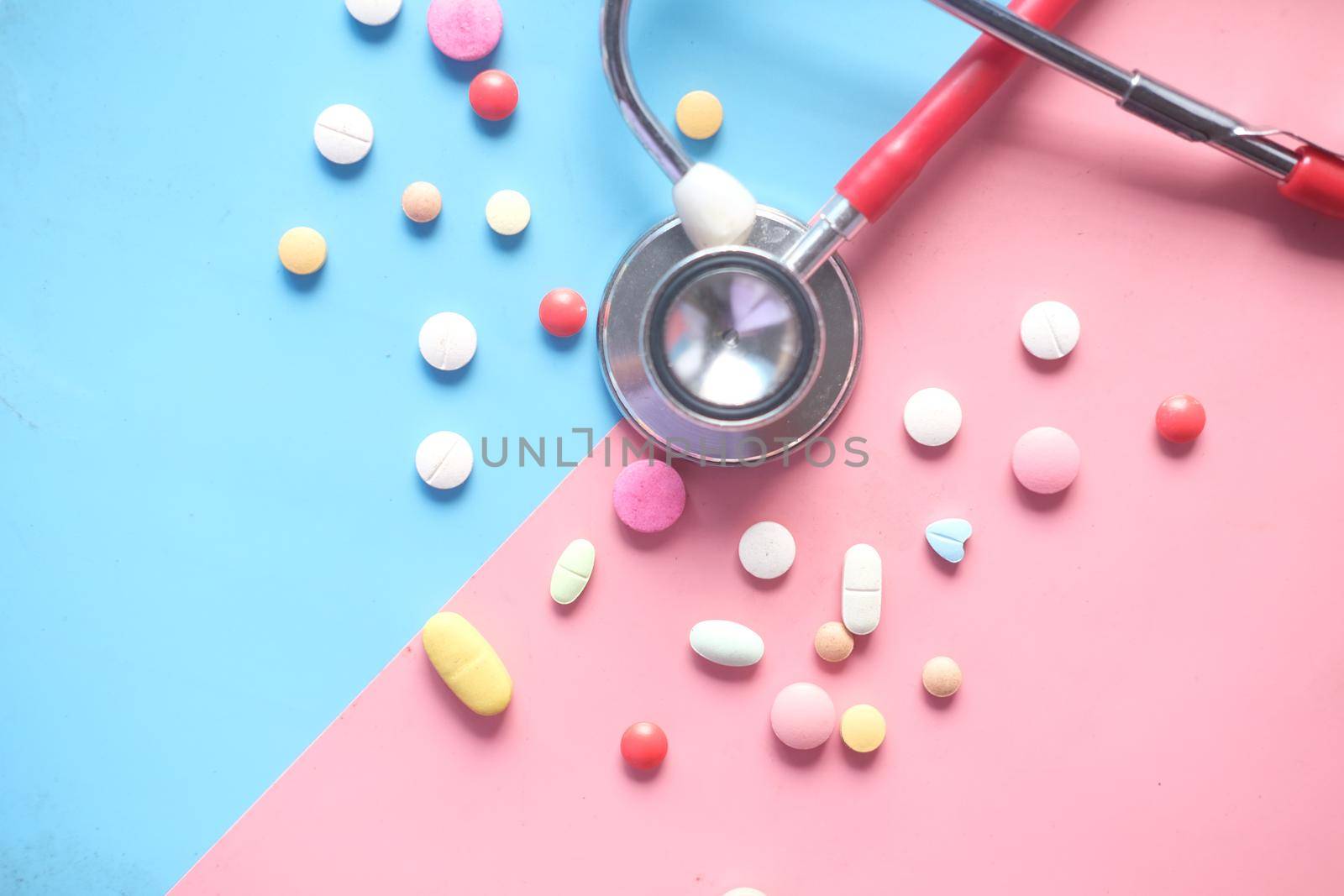 colorful medical pills and stethoscope on color background .