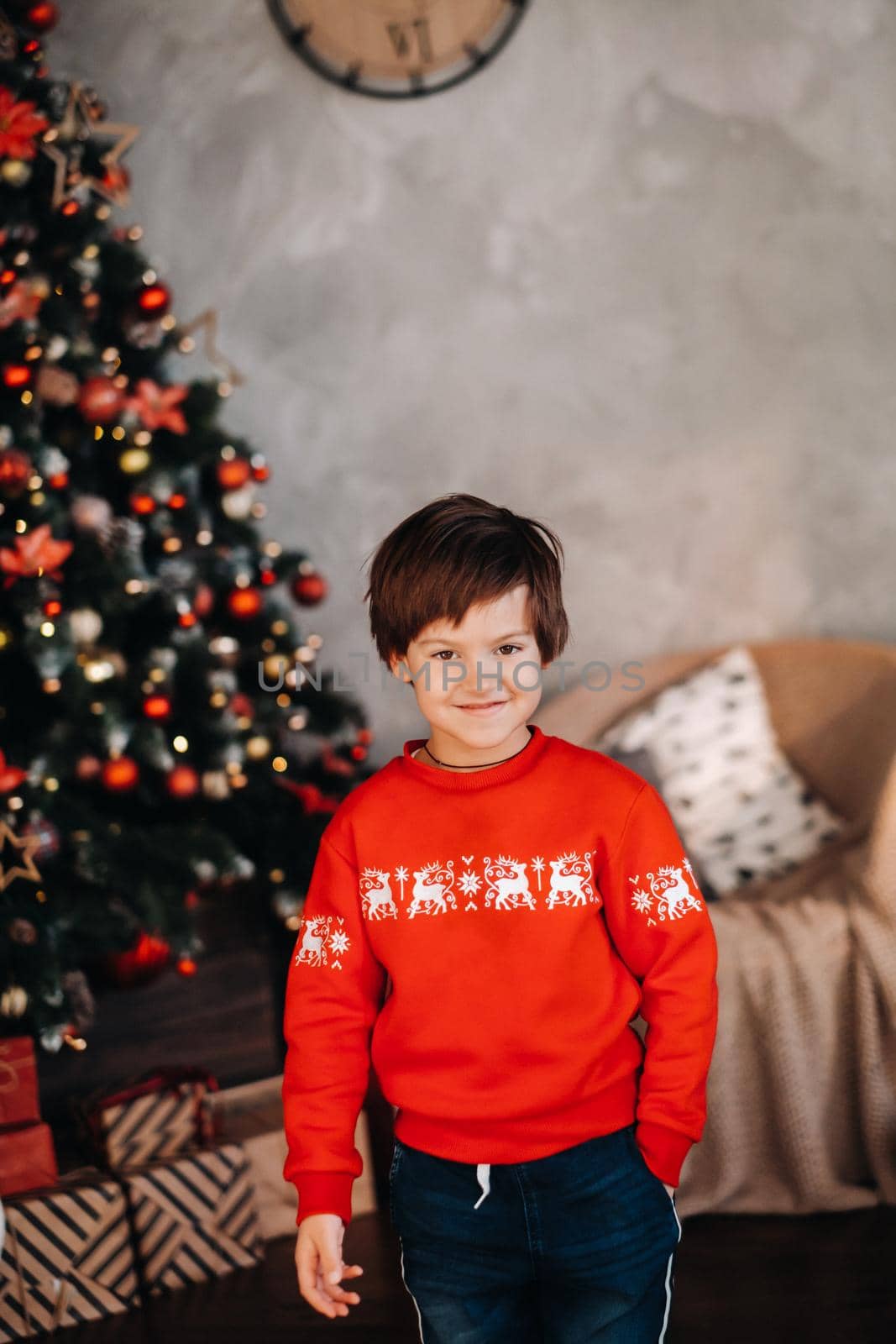 portrait of a smiling boy standing at the Christmas tree at home.