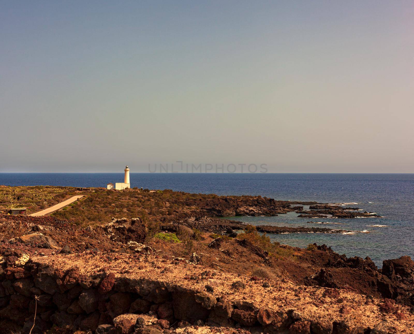 View of lighthouse in the scenic lava rock cliff, Linosa by bepsimage