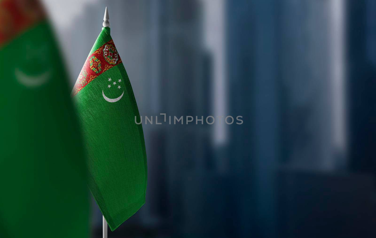 Small flags of Turkmenistan on a blurry background of the city.