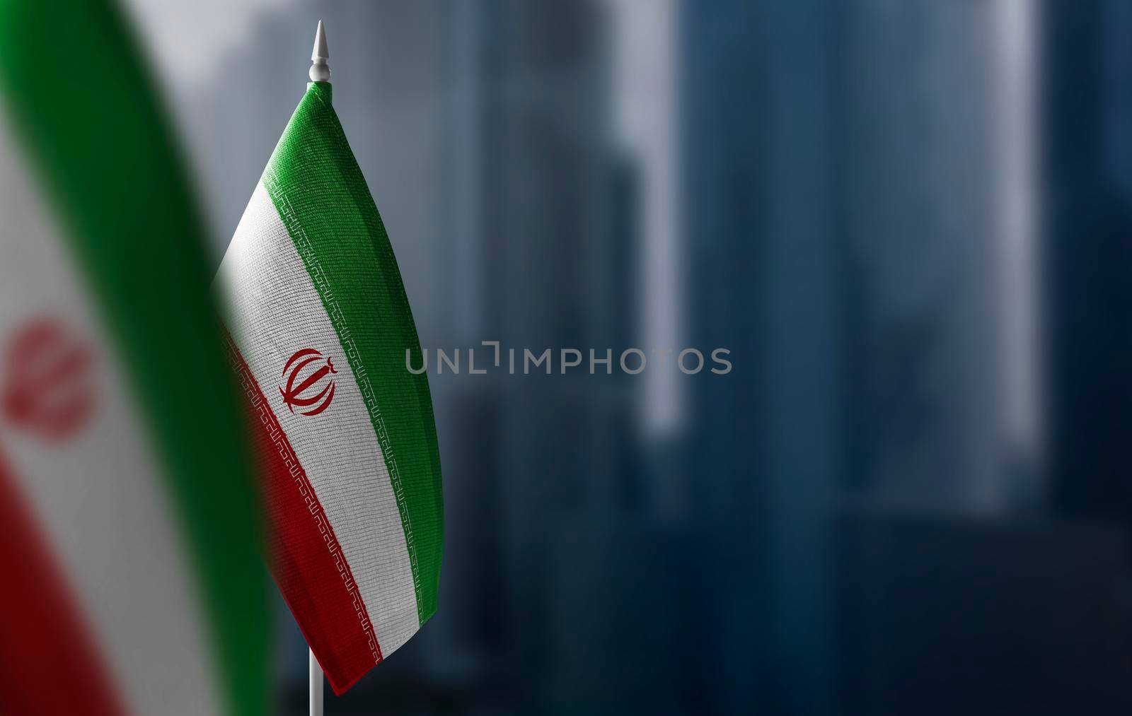 Small flags of Iran on a blurry background of the city.