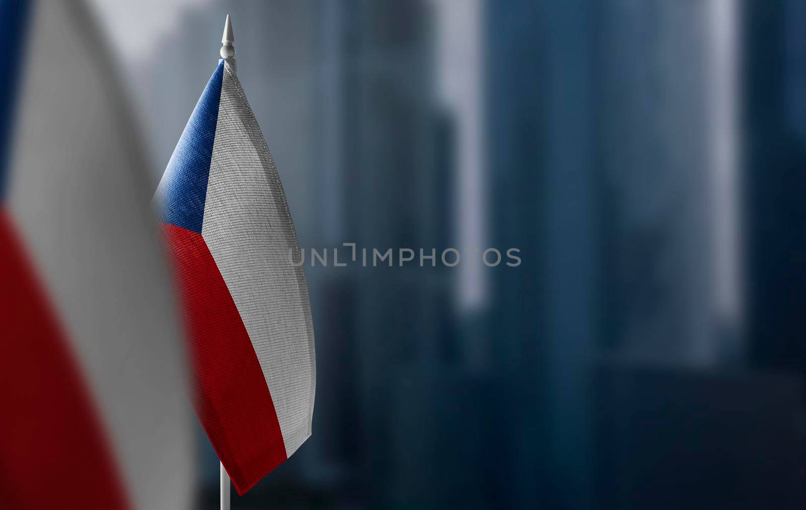 Small flags of Czechia on a blurry background of the city.