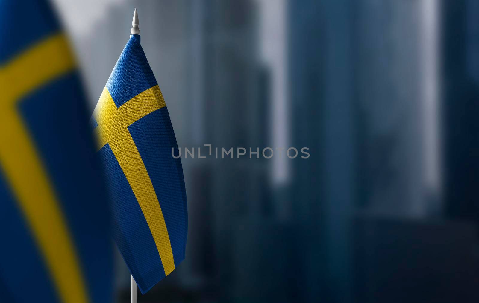Small flags of Sweden on a blurry background of the city.