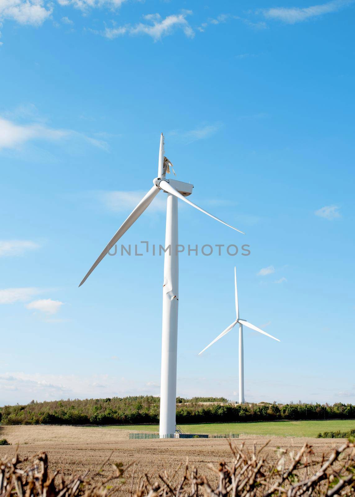 Electricity power wind turbine with broken blade and damaged tower awaiting repair after accident.