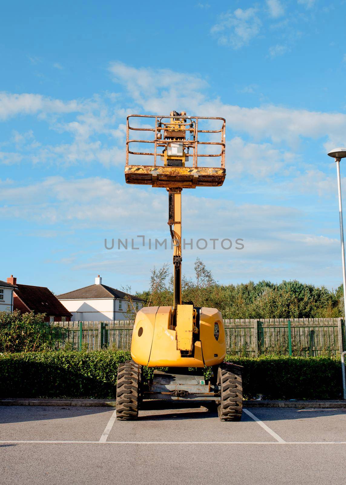 Telescopic boom lift raised up on blue sky background delivered to construction site ready to be used by steel frame erectors, roofers and painters on parking by Iryna_Melnyk