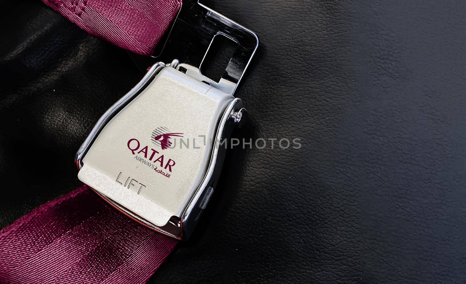 Doha, Qatar July 2021: purple lap belt of an empty seat inside an airplane with the Qatar Airways logo printed on the metal.