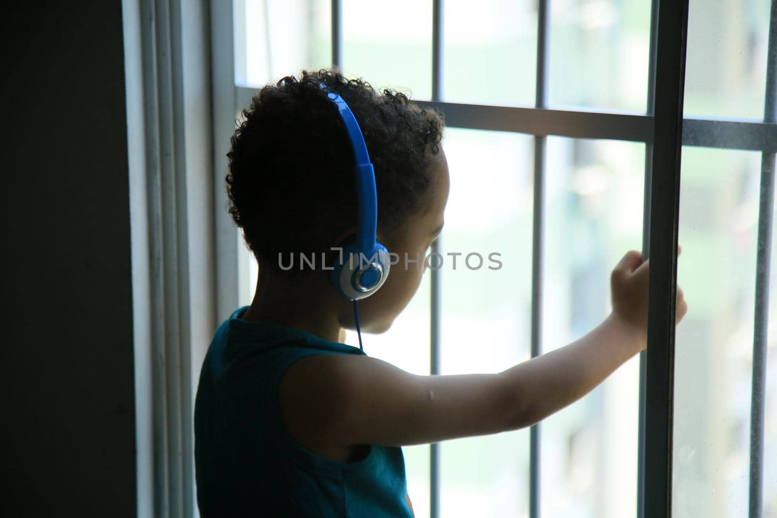 child wearing headphone in window by joasouza