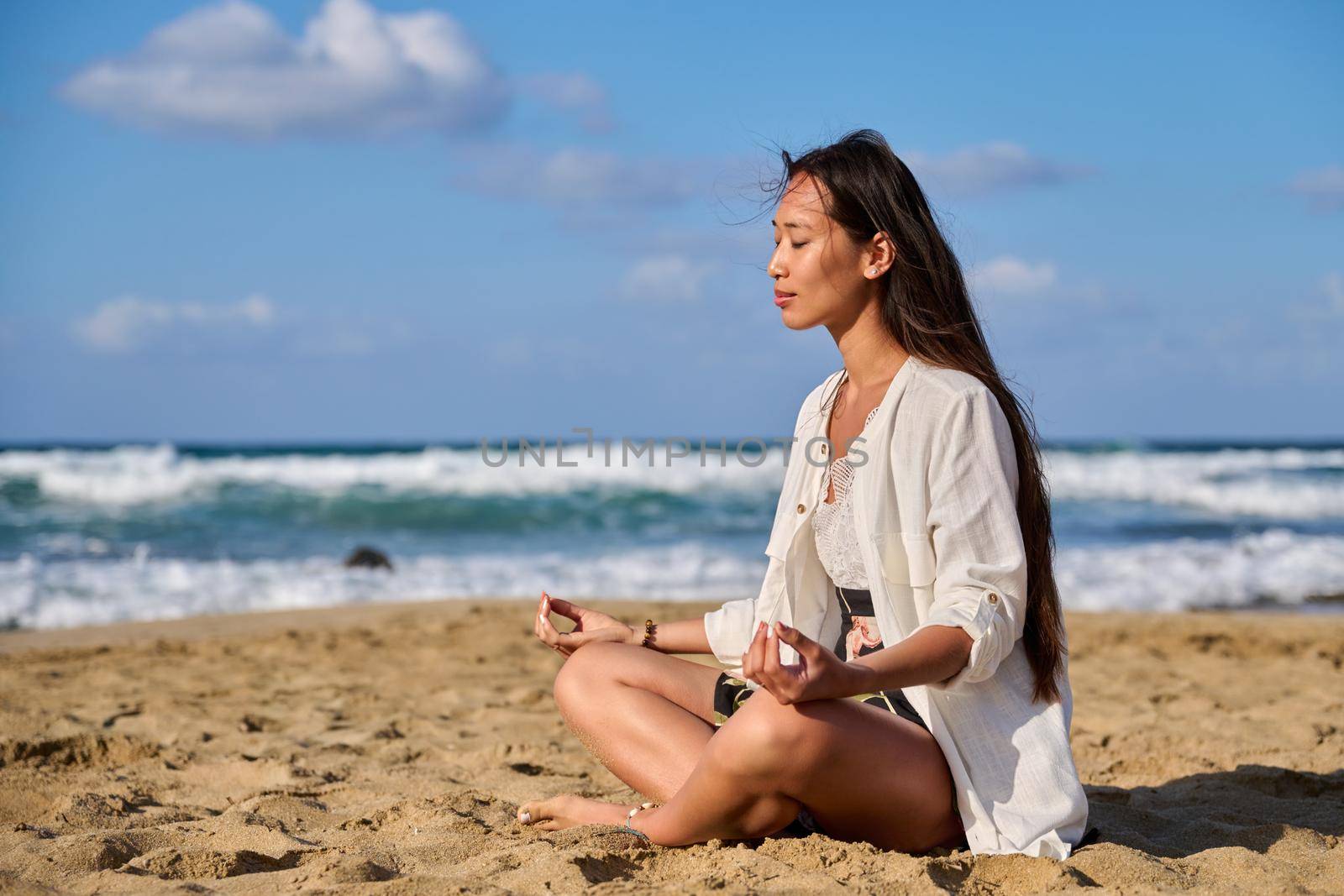 Young beautiful woman in lotus position meditating on the beach by VH-studio