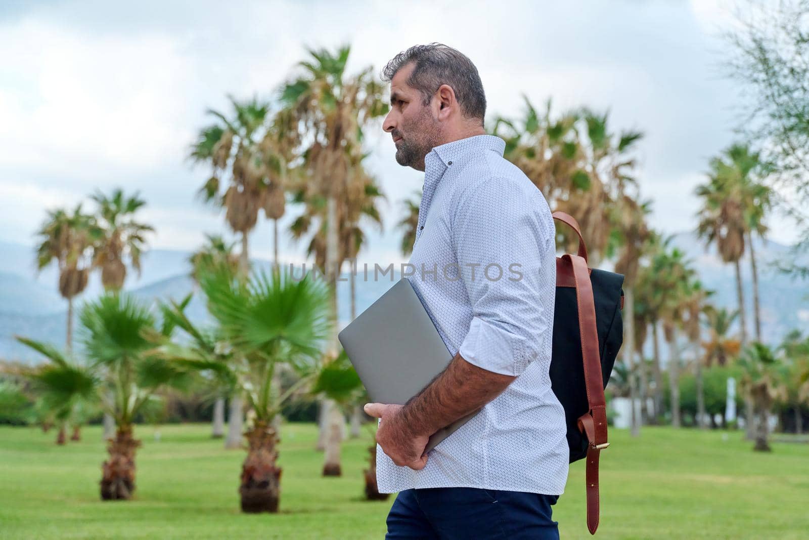 Portrait of serious confident mature man with laptop outdoors by VH-studio
