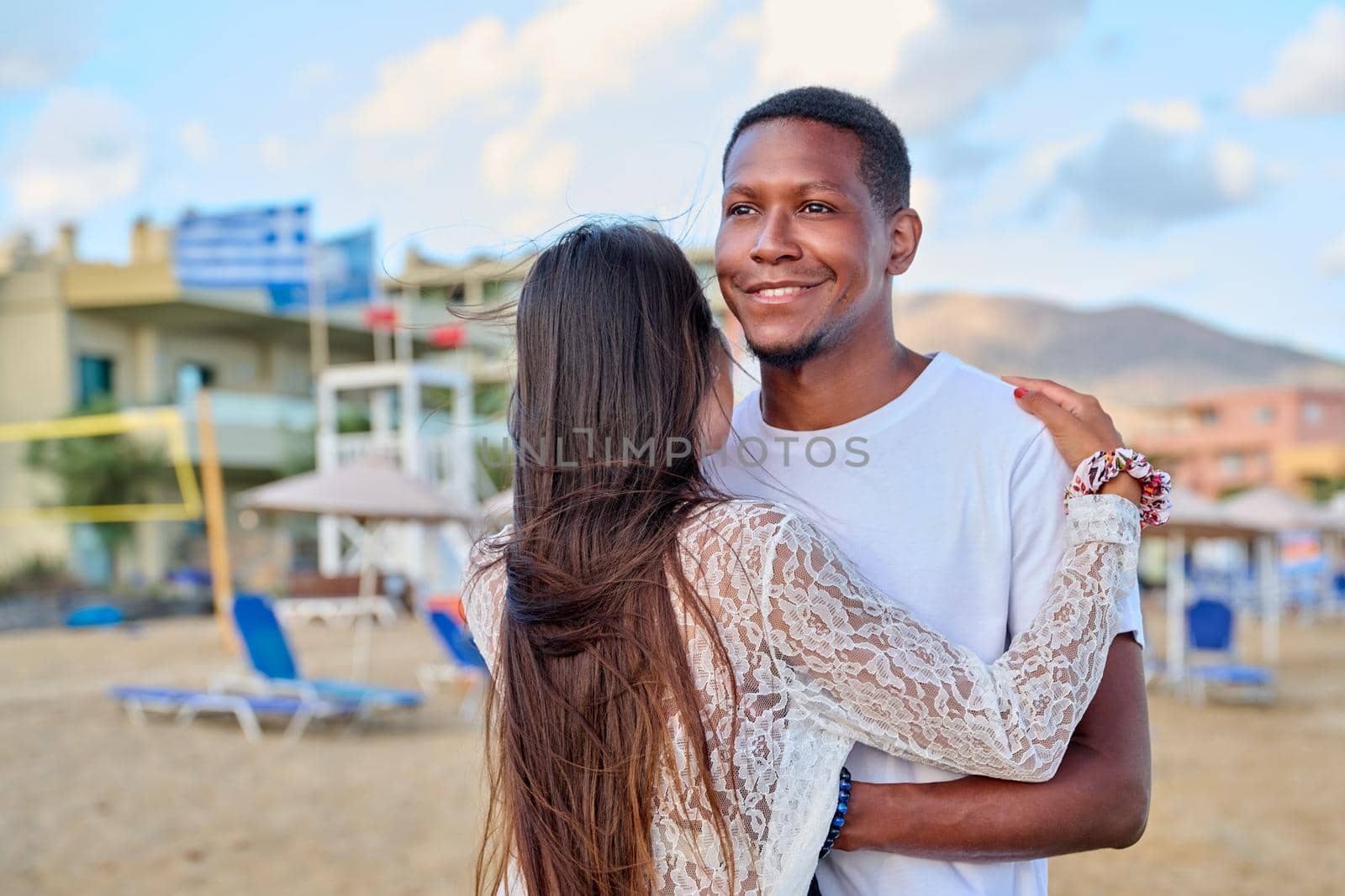Happy young couple hugging, man's face close up. Multiculturial couple, african american man looking to side on summer beach, relationship, love, happiness, people, family, tourism, travel