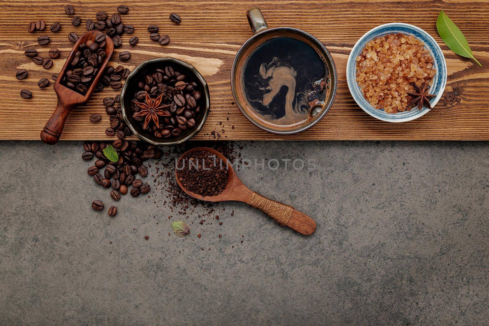 Roasted coffee beans with coffee cup setup on dark stone background. by kerdkanno