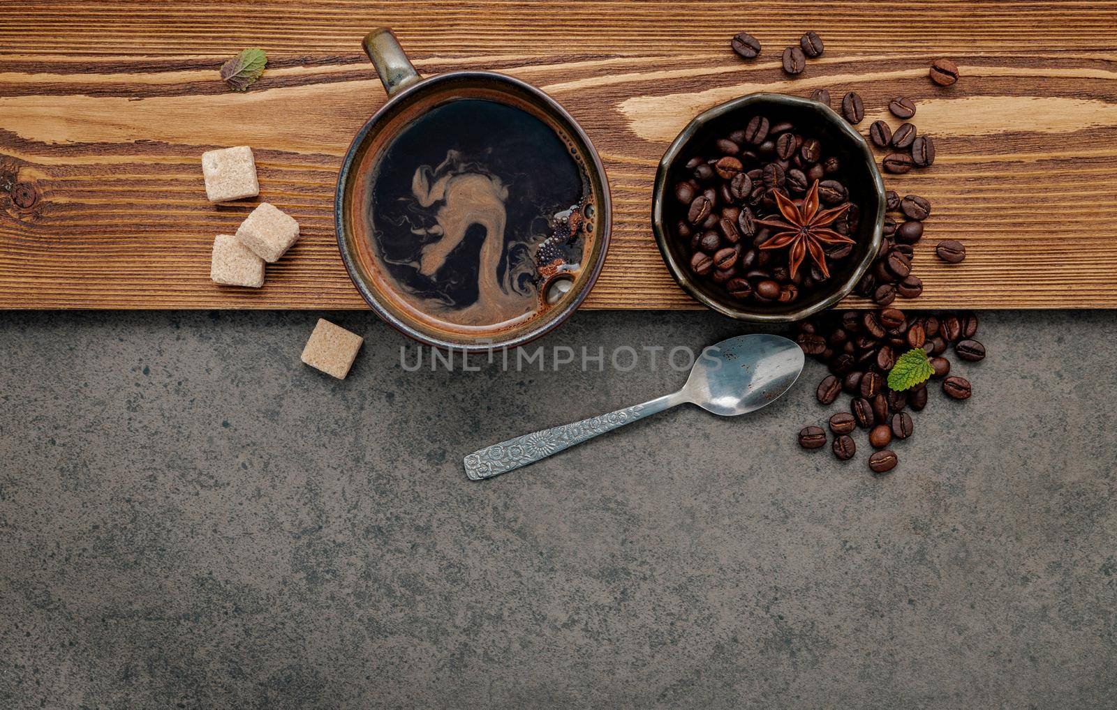 Roasted coffee beans with coffee cup setup on dark stone background. by kerdkanno