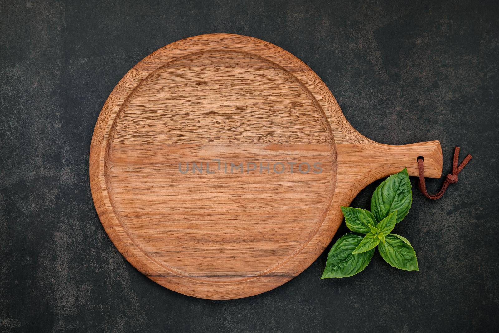 Empty wooden pizza platter set up on dark concrete. Pizza tray on dark concrete background flat lay and copy space. by kerdkanno