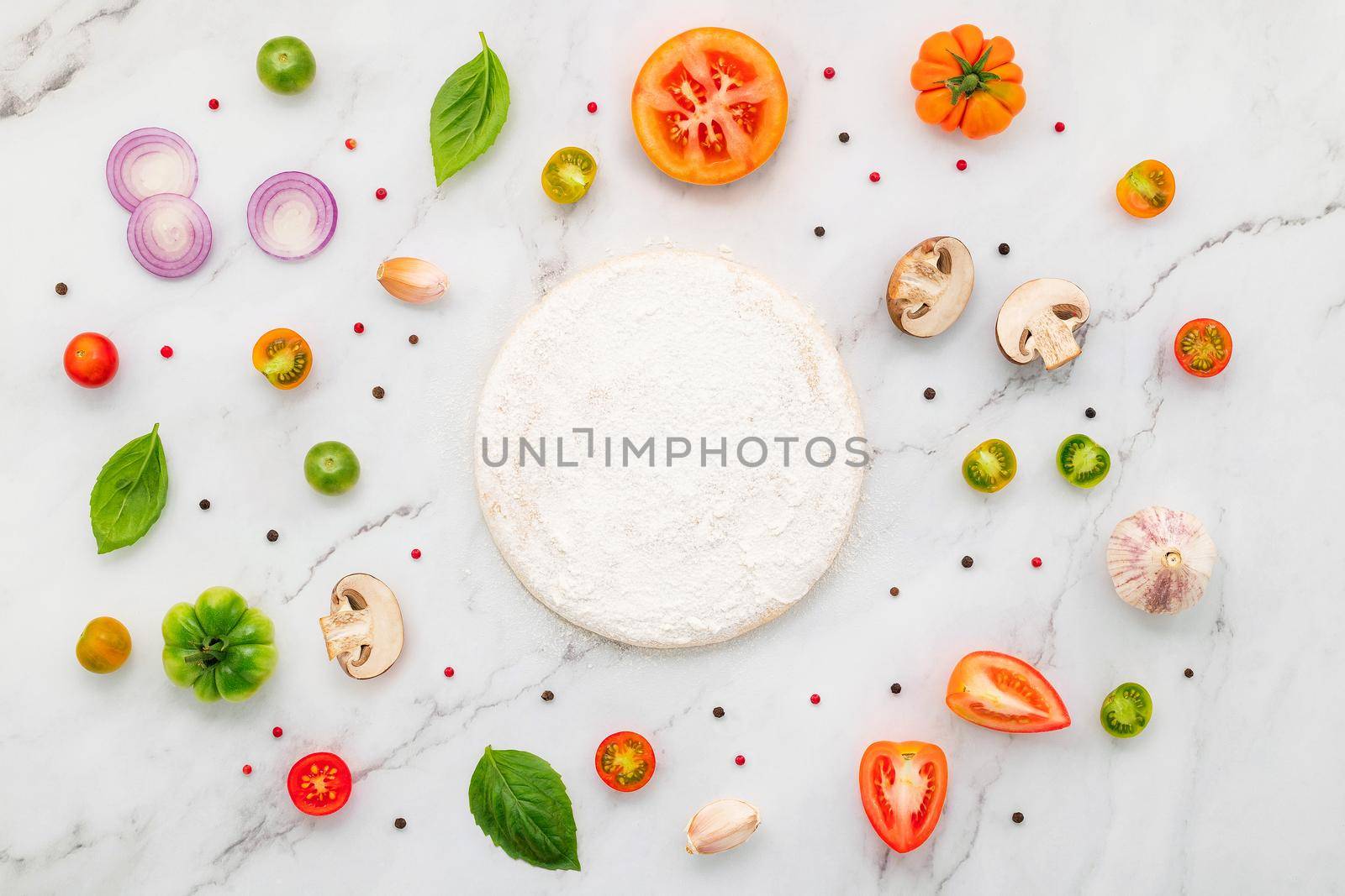 The ingredients for homemade pizza set up on white marble background.