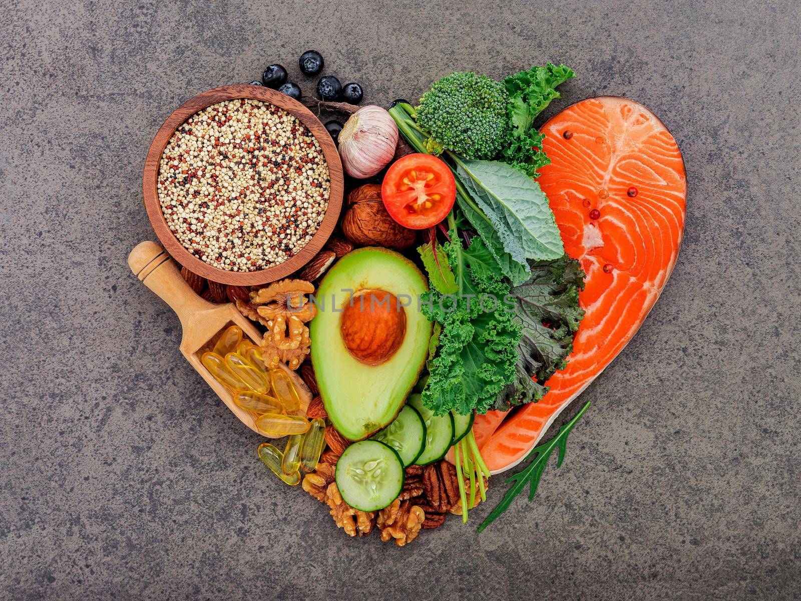 Heart shape of ketogenic low carbs diet concept. Ingredients for healthy foods selection on dark stone background.