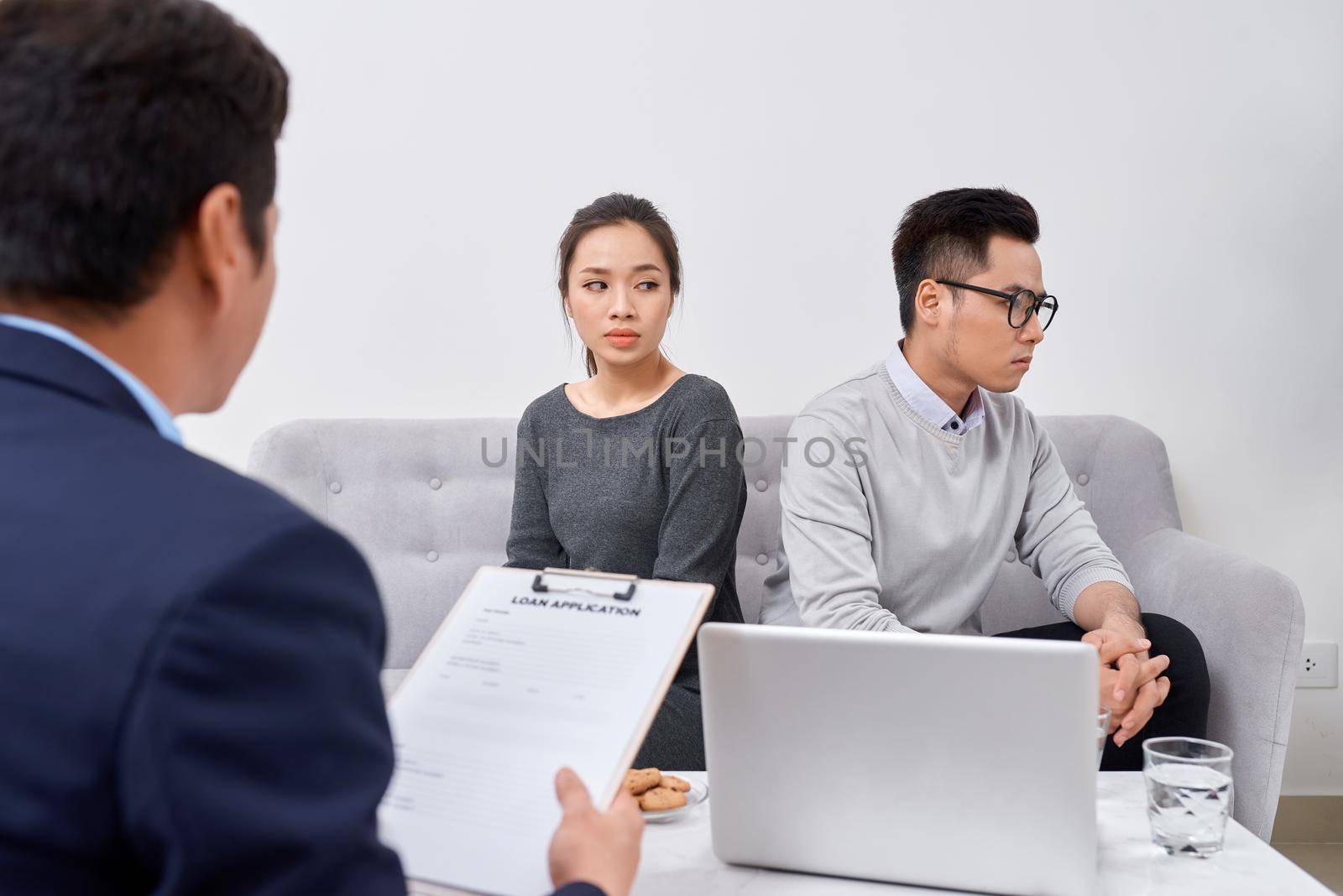 It is not my fault! Displeased young man talking to psychiatrist and gesturing while his wife sitting near him and keeping arms crossed