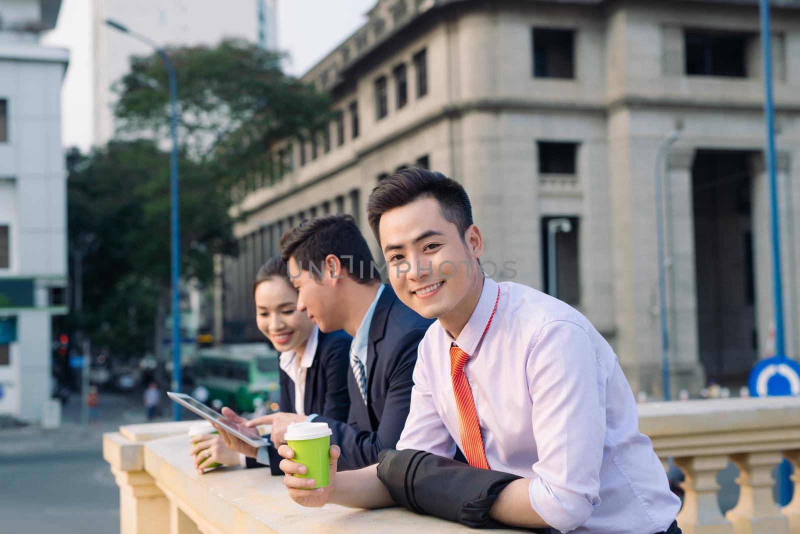 Asian business woman and men having coffee break outside in front of building by makidotvn
