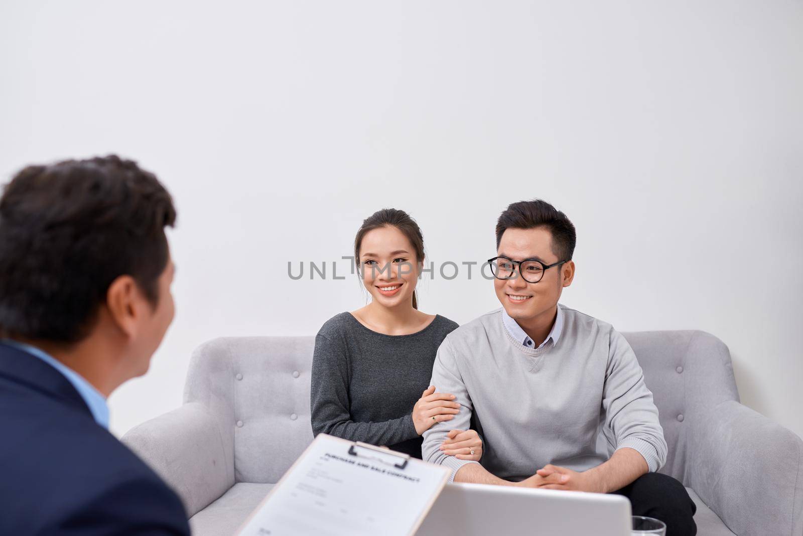 Happy young couple hold each other hands listening to female agent, planning wedding, consulting investment advisor, hearing good news, casual marriage registration, buying real estate