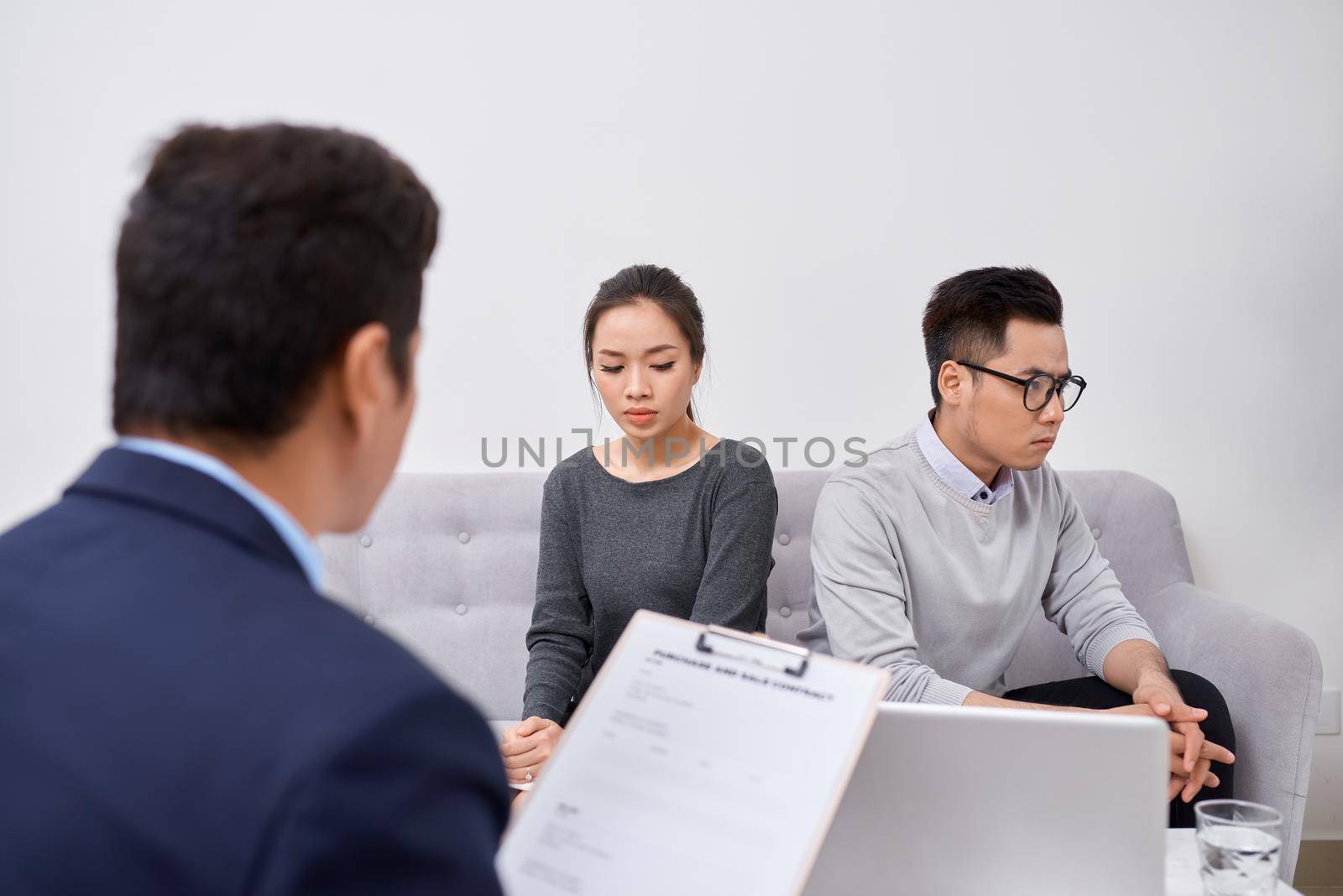 Young angry couple of cheated investors holding papers arguing with male real estate agent, defrauded property purchasers protecting their rights, too high interest rate of banking loan or mortgage