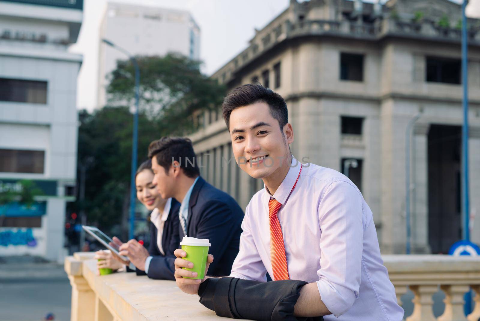 Asian business woman and men having coffee break outside in front of building by makidotvn