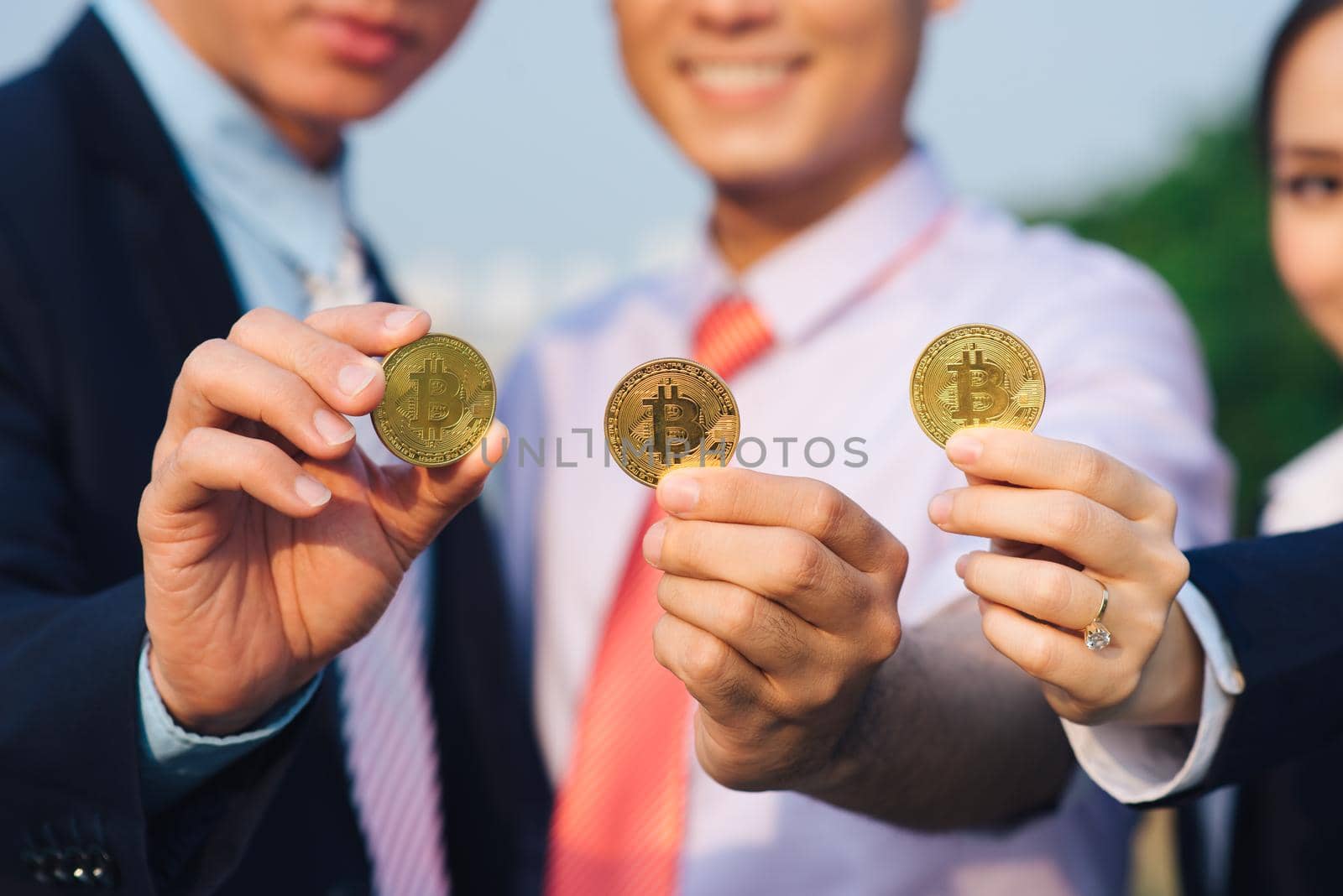 Young Asian Businessman holding golden bitcoin in front of his international Multi ethnic team in modern city. by makidotvn