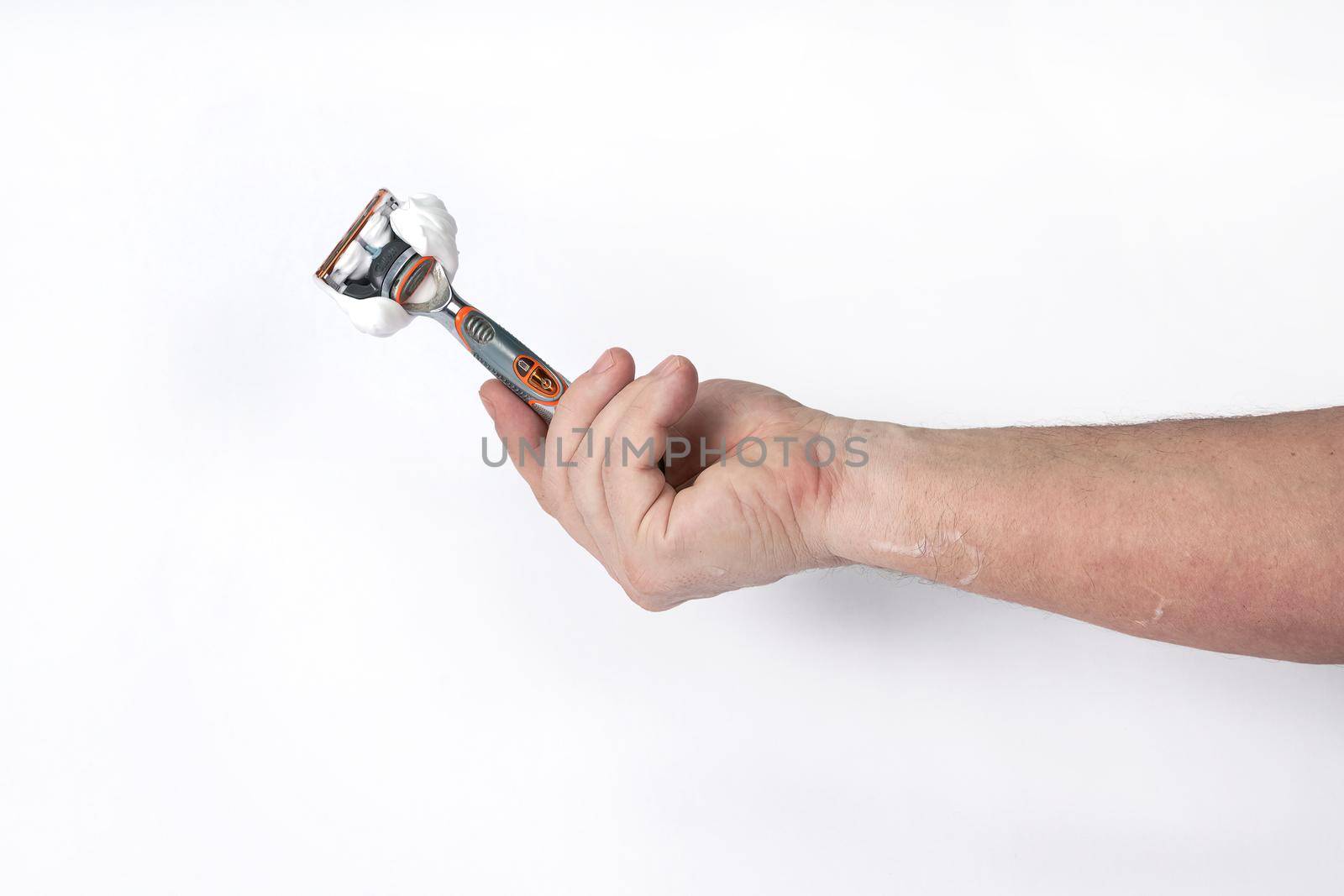 Hand holds a shaving razor with shaving foam on a white background, a template for designers. Close-up