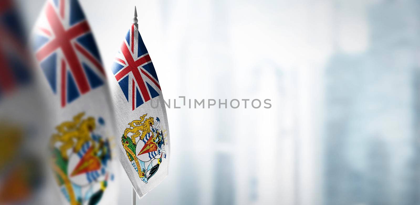 Small flags of British Antarctic Territory on a blurry background of the city.