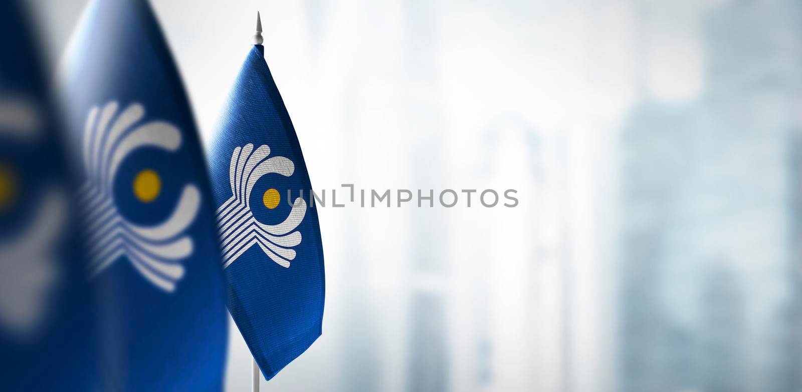 Small flags of CIS on a blurry background of the city.