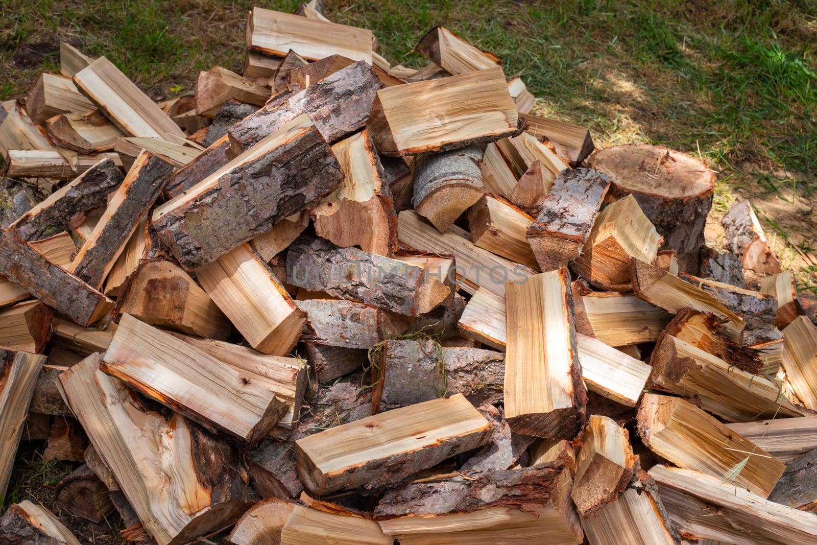 Chopped wood in a heap outside, prepared for the winter to heat the house. Fuel for stove and fireplace.