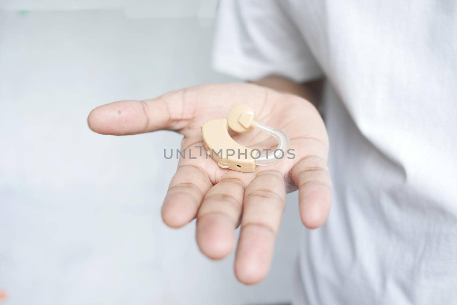 hand hold a Hearing aid equipment against white background .