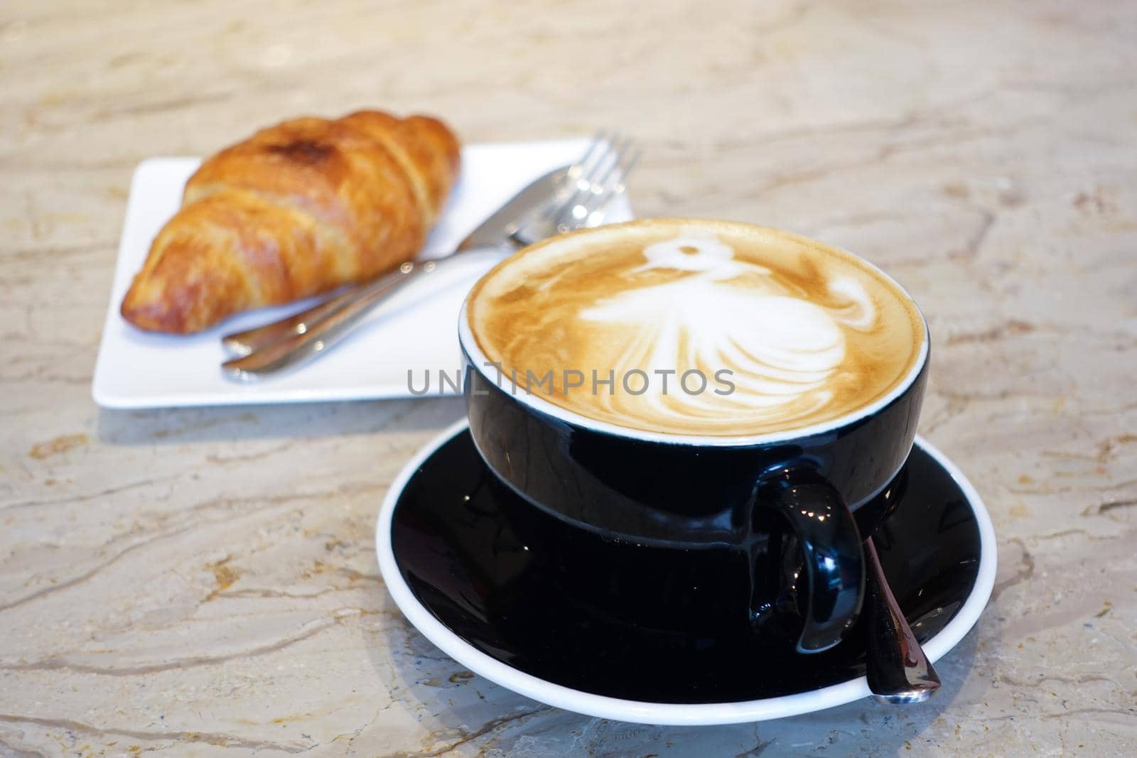 a cup of late coffee with flower shape design on top at cafe .