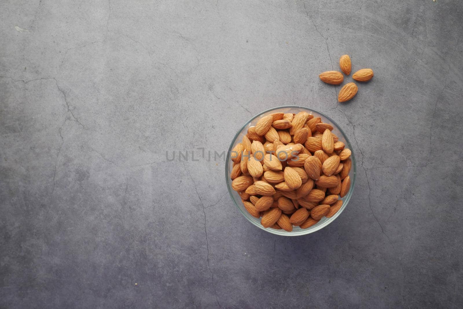 top view of almond nuts in a bowl on black background .