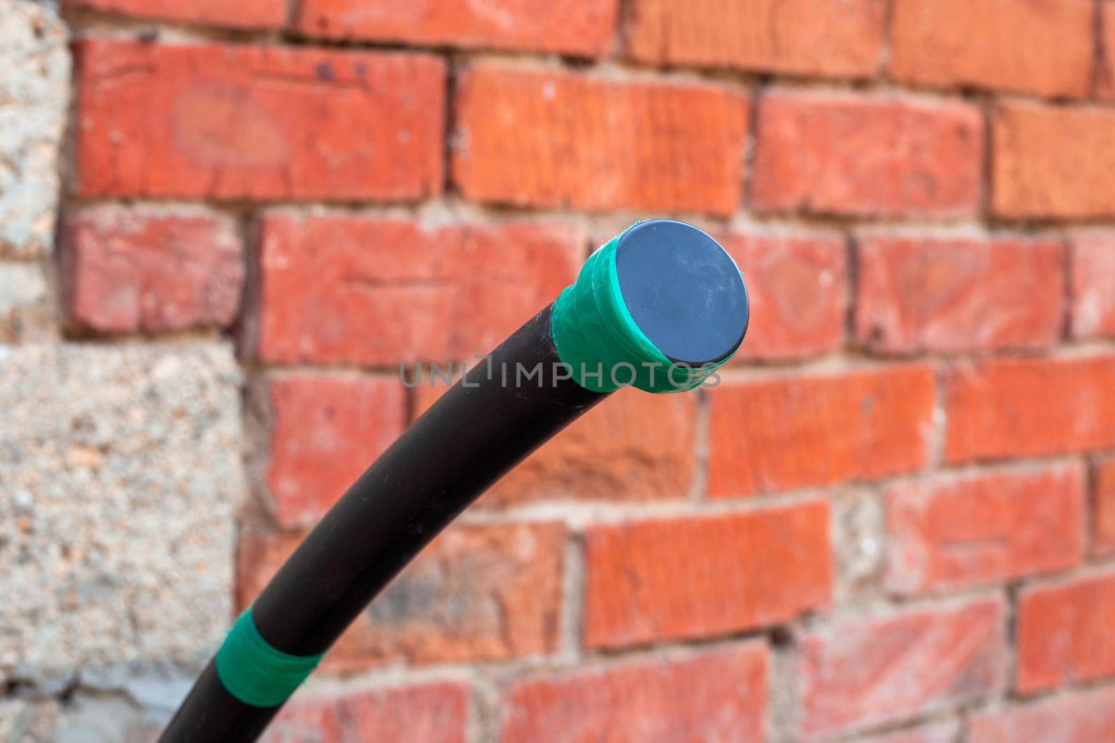 Water supply polyethylene pipe with a plug on the background of a brick wall. Plumbing in a country house.