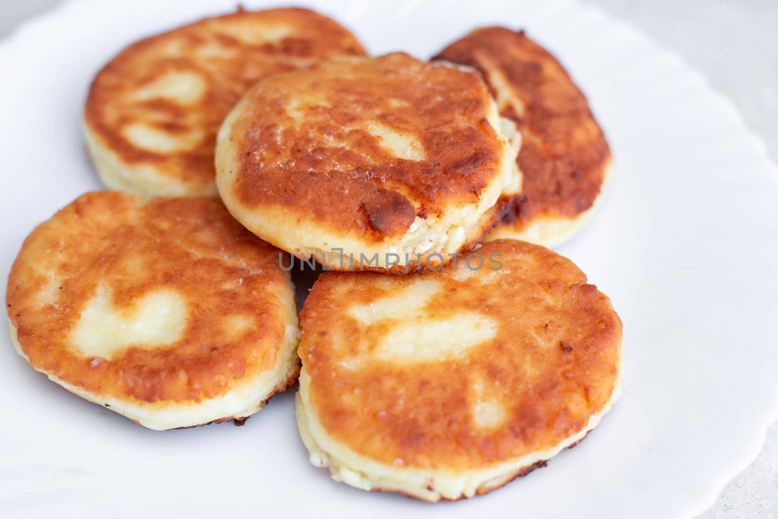 Fresh fried cheesecakes on a white plate, close-up. Delicious healthy breakfast.