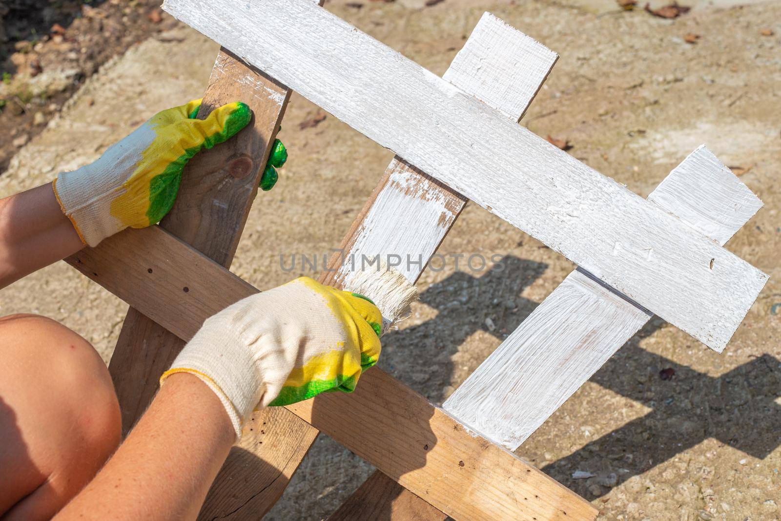 A woman paints a fence for a flower bed. Making and painting a decorative fence for a garden.