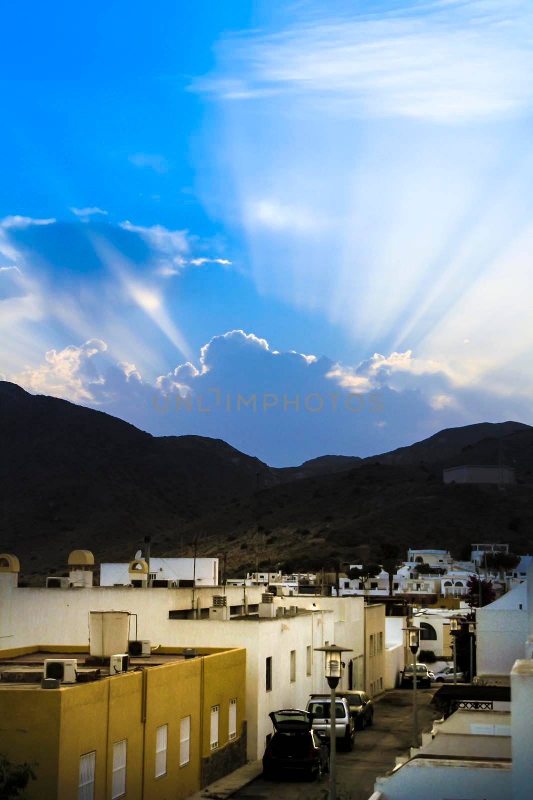 Pozo de los Frailes, Almeria, Spain- September 7, 2021:Pozo de los Frailes village and Sunbeam shining trough cloudy sky before sunset to mountain range