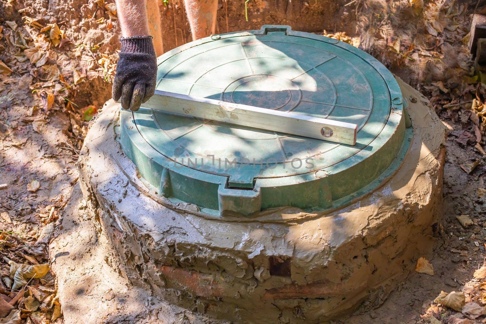 Installation of a septic tank with a well made of concrete rings. Leveling the hatch cover.