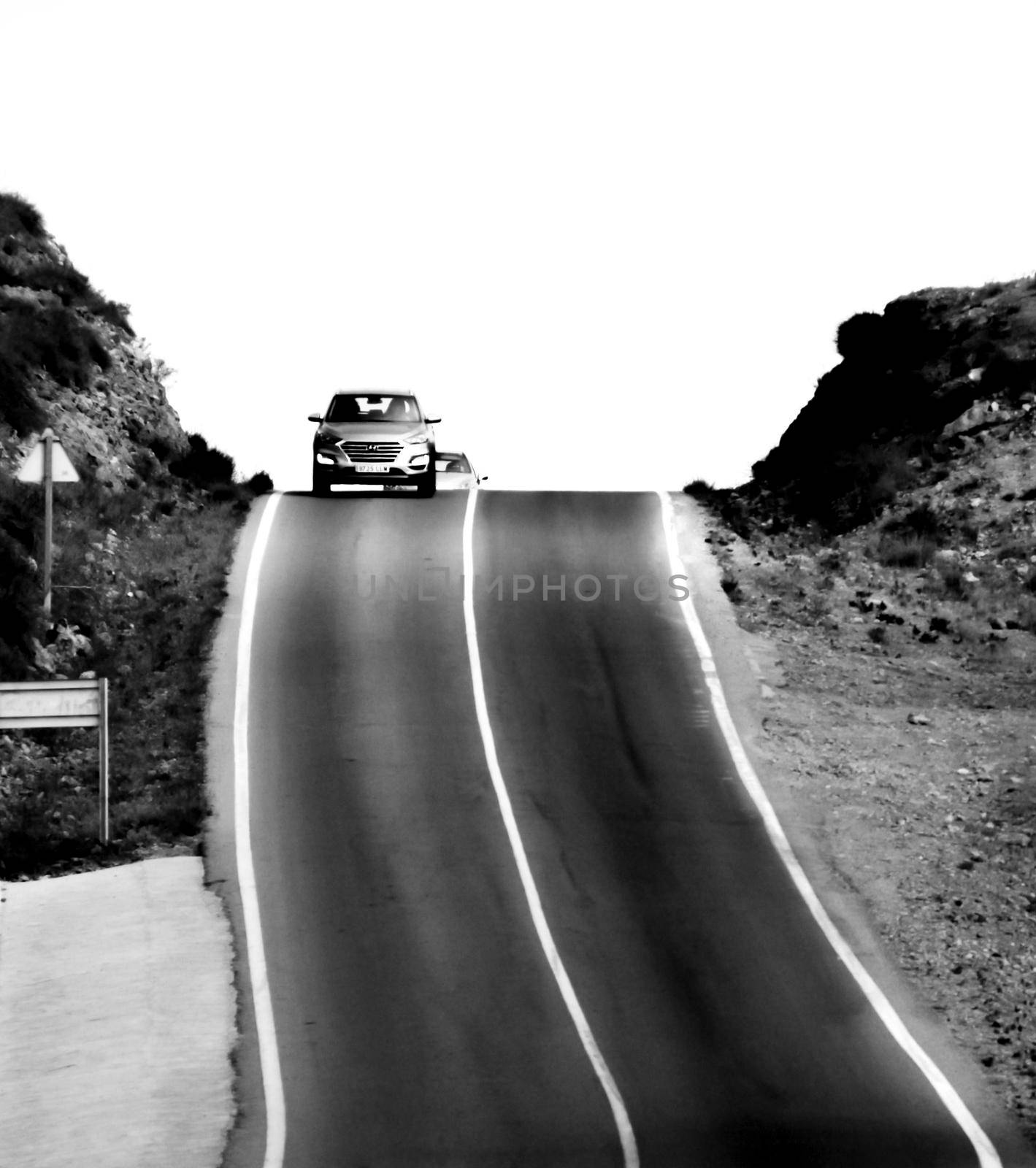 Dizzying road with traffic sign in Spain. Monochrome picture
