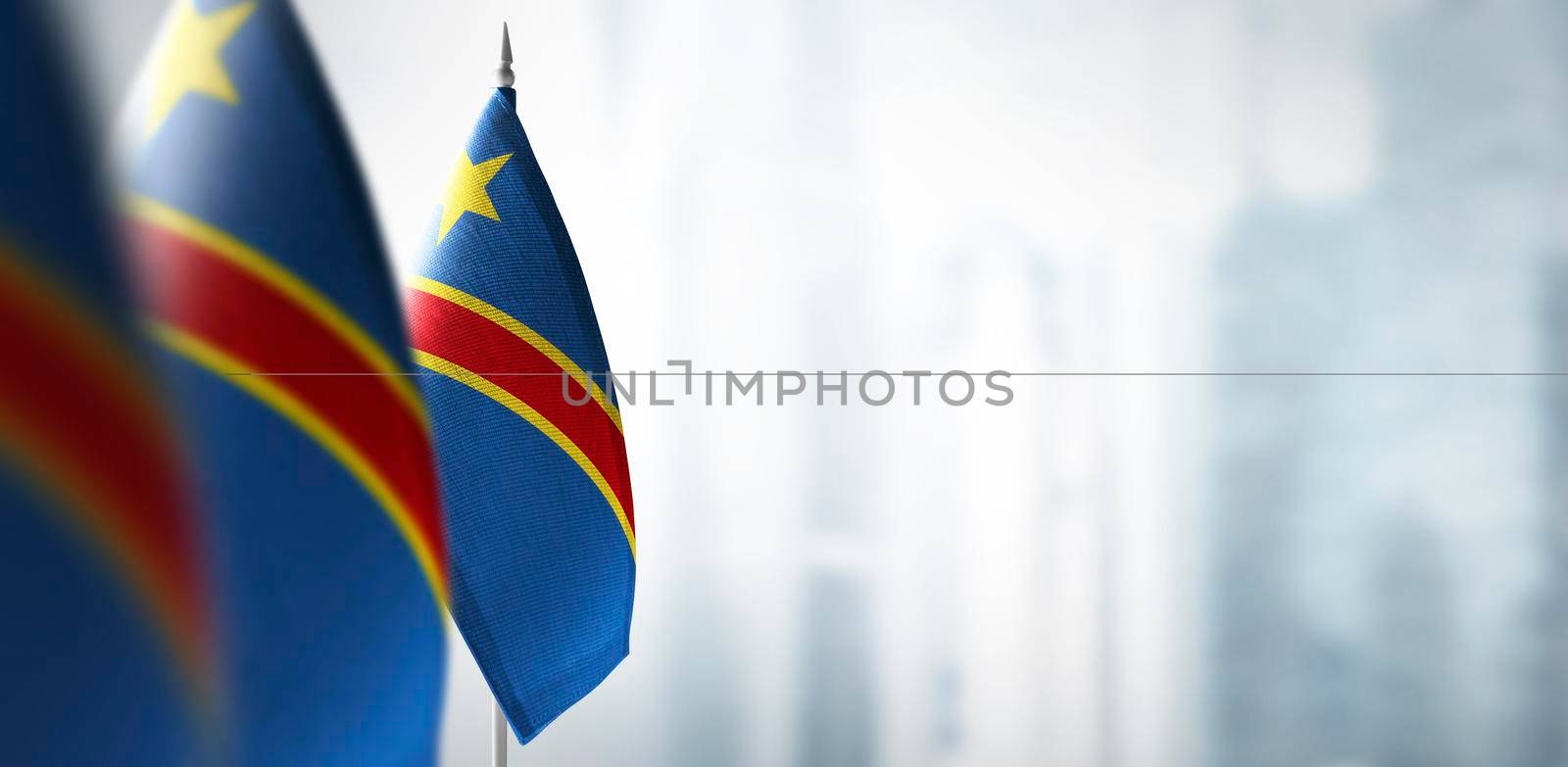 Small flags of Democratic Republic of the Congo on a blurry background of the city.