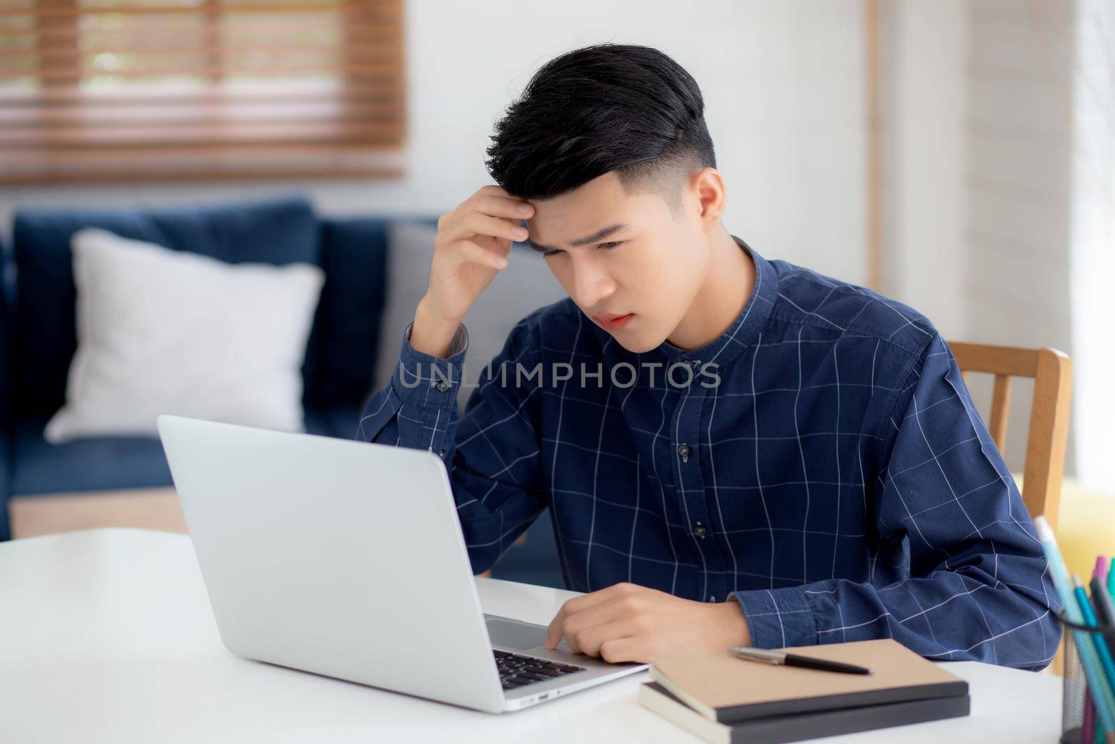 Young asian business man headache during working on laptop computer with deadline on desk at home, businessman with failure exhausted and tired, stress and worried, frustrated and unsuccessful. by nnudoo